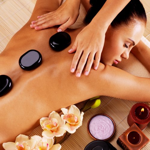 Adult woman having hot stone massage in spa salon